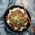 korean beef and rice bowl with green onions and sesame