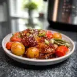 slow cooker honey garlic chicken and veggies plated with sesame garnish on modern marble countertop